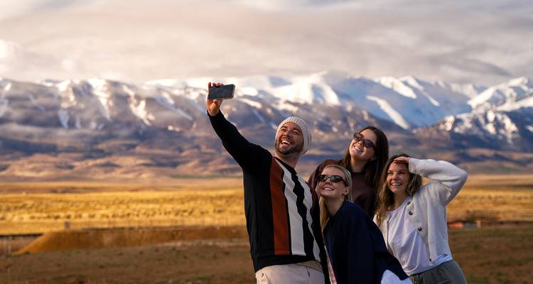 Un groupe prend un selfie avec des montagnes enneigées qui s'étendent à l'horizon.