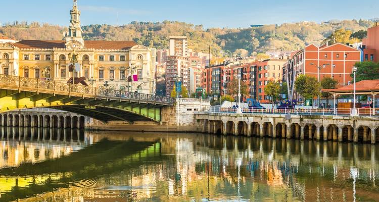 Rive de Bilbao avec l'hôtel de ville orné, le pont en arche et le reflet coloré dans la rivière Nervión.