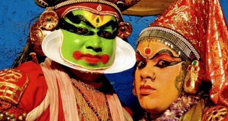 Two Kathakali performers in elaborate colorful makeup and ornate costumes pose for the camera