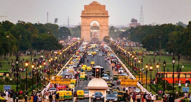 Geschäftiger Verkehr und Menschenmengen säumen den Boulevard zum India Gate in der Abenddämmerung