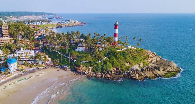 Vibrant aerial view of a red-and-white lighthouse on a coconut-lined headland beside a golden beach and turquoise sea.