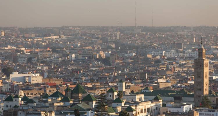 Wazig stadsgezicht van Marrakech met daken en de minaret van de Koutoubia-moskee bij schemering