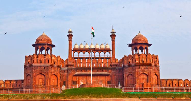 Vue de face du majestueux Fort Rouge avec le drapeau indien flottant haut sous un ciel bleu pâle avec des oiseaux.