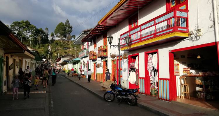 Rue colorée de Salento avec des balcons brillants, des boutiques et des habitants qui se promènent