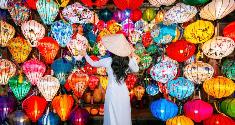 Mujer en ao dai tradicional admira una deslumbrante pared de linternas multicolores en Hoi An