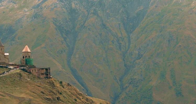 Solitary hill-top church and watchtower perched above a vast, rugged mountain valley.