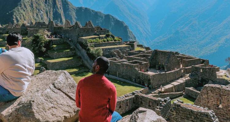 Visitors sit and admire the stone ruins of Machu Picchu perched high in the Andes.