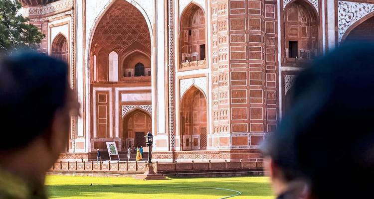 Partial view of ornate Mughal gateway at the Taj Mahal complex framed by observers