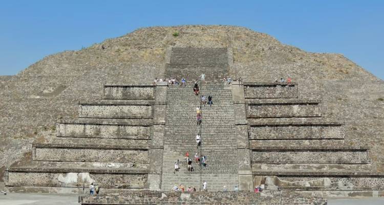 La Pyramide de la Lune aux marches successives s'élève sous un ciel bleu dégagé alors que les visiteurs gravissent son escalier central.