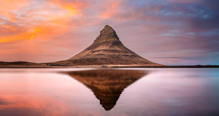 Iconische Kirkjufell berg perfect weerspiegeld in kalme wateren onder een kleurrijke zonsopganghemel