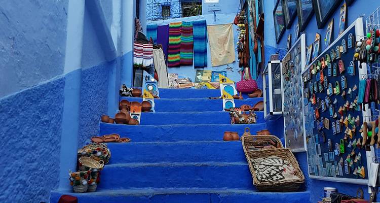 Vue rapprochée de marches bleues couvertes d'artisanat et de souvenirs à Chefchaouen.