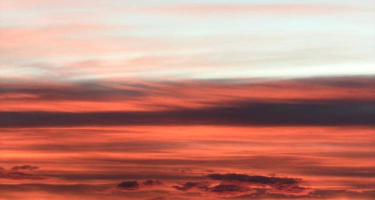 Nuages stratifiés rouge vif et orange pendant un coucher de soleil coloré dans le désert.