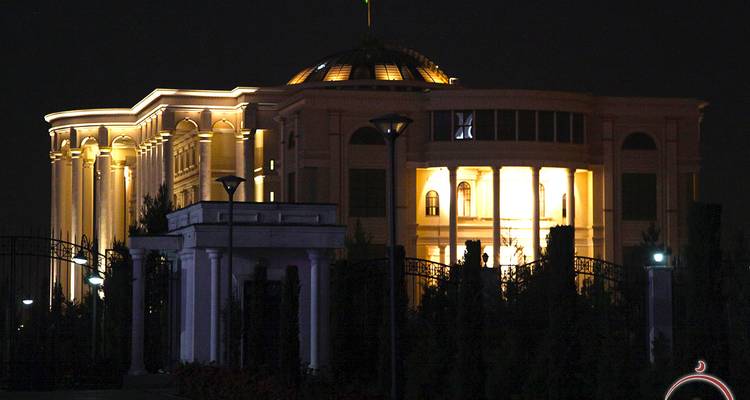 Indrukwekkend regeringsgebouw 's nachts verlicht met gouden lampen tegen een donkere hemel.