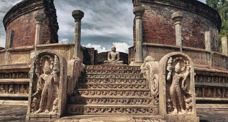 Ancient circular brick stupa with ornate carved guard stones and Buddha statue at Polonnaruwa ruins.