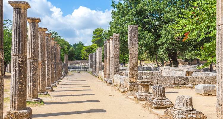 Rij van oude zuilen en gevallen kapitelen op de archeologische vindplaats van Olympia.