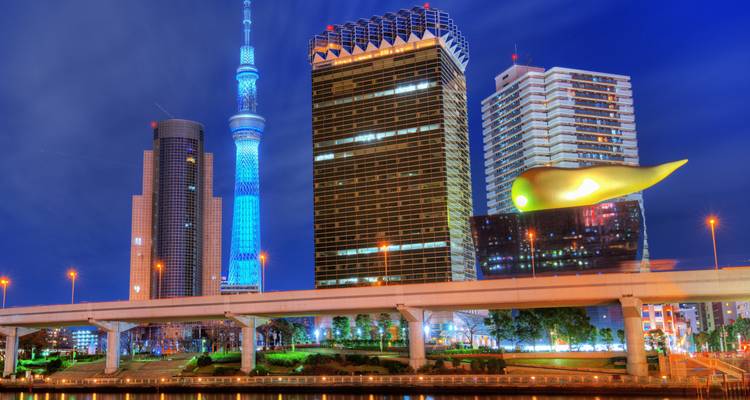 L'horizon illuminé de Tokyo avec la Skytree éclairée en bleu et la Flamme dorée d'Asahi se détachant contre le ciel nocturne.