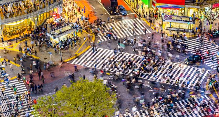 Unscharfe Aufnahme von Hunderten von Menschen, die nachts die berühmte Shibuya-Scramble-Kreuzung in Tokio überqueren