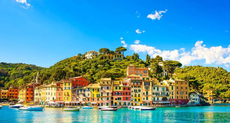 Puerto pintoresco de Portofino con edificios de colores brillantes reflejados en aguas turquesas tranquilas bajo un cielo despejado.