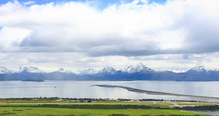 Panoramic view over Homer Spit extending into Kachemak Bay with snow-capped ranges beyond.
