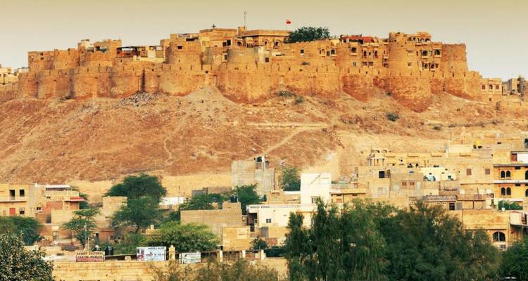 Golden sandstone Jaisalmer Fort dominating hilltop above desert cityscape.