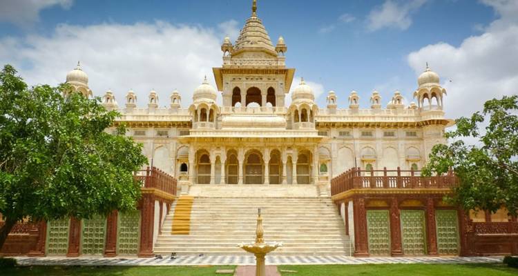 Elegant white marble cenotaph with domes and ornate pillars surrounded by gardens under a blue sky in Jodhpur.