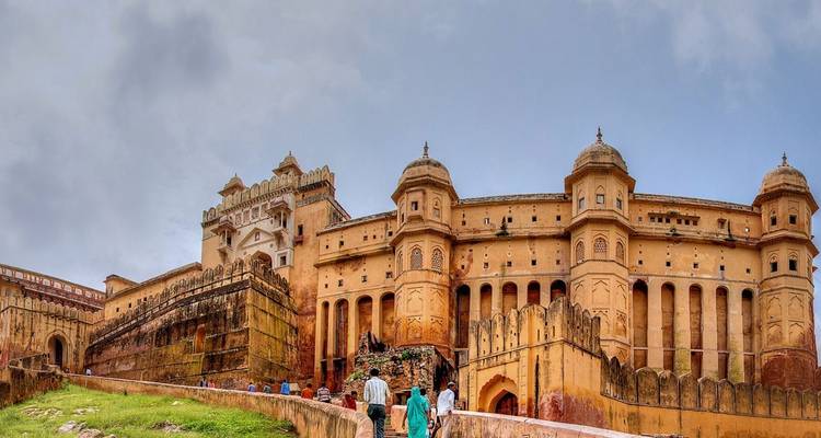 Tourists approaching the massive Amber Fort walls and ornate gateways under a bright sky.