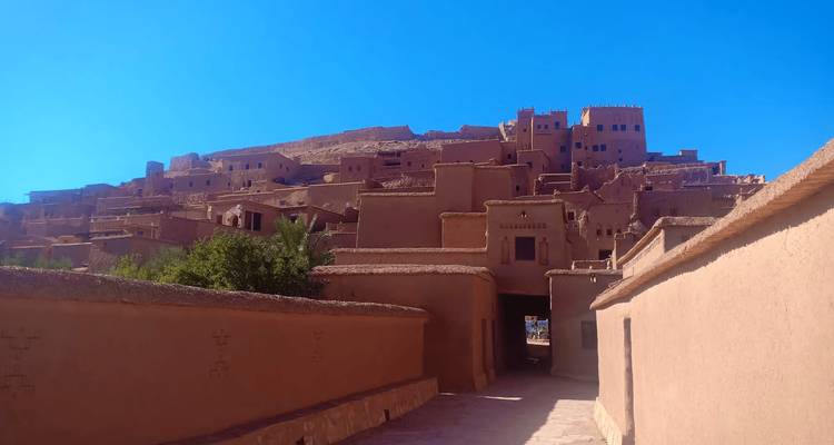 Sendero que conduce hacia los edificios de adobe de Ait Benhaddou bajo un cielo azul profundo