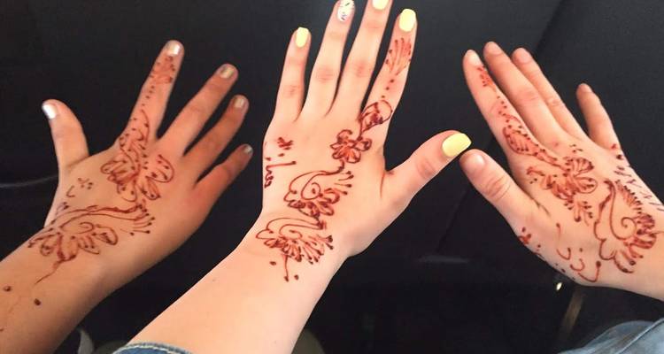 Tres manos muestran diseños de henna frescos e intrincados.