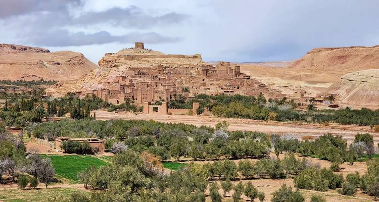 Ksar de Ait Benhaddou visto a través de un oasis verde con dramáticas colinas desérticas detrás