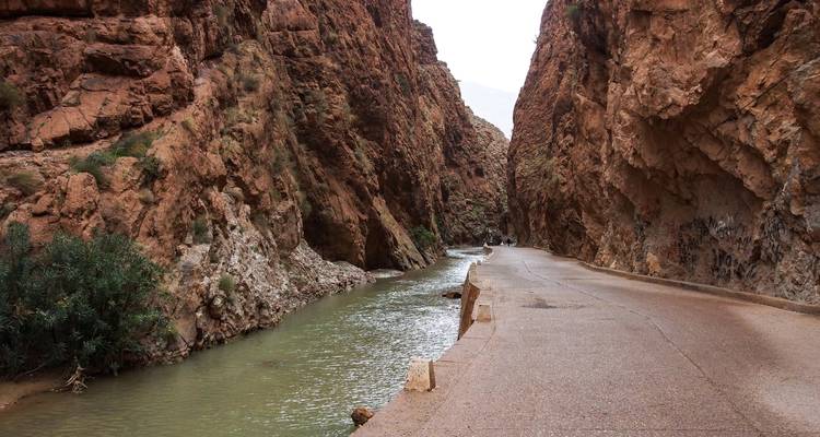 Estrecho corredor de cañón con río fluyendo junto a una tranquila carretera asfaltada