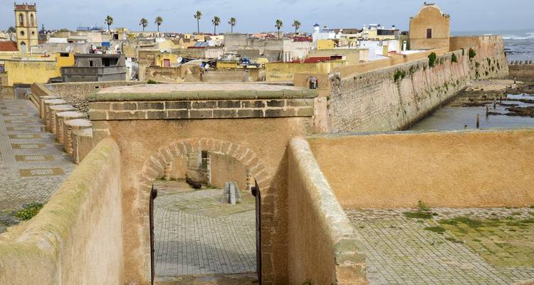 Coastal fortified walls and ramparts overlooking a low-tide shoreline and old town.