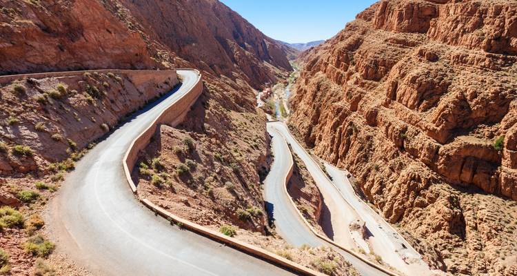 Dramatic switchback mountain road winding through a reddish canyon.