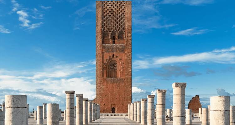 Hassan Tower rising above rows of white stone columns under a vivid blue sky.