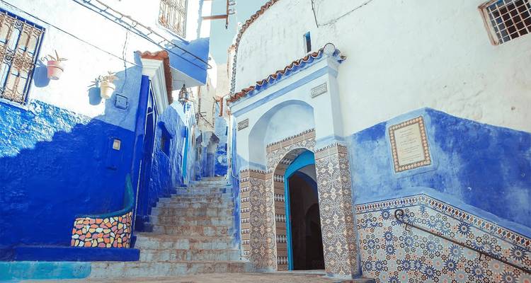 Blue-and-white stairway and tiled archway inside a Moroccan medina.