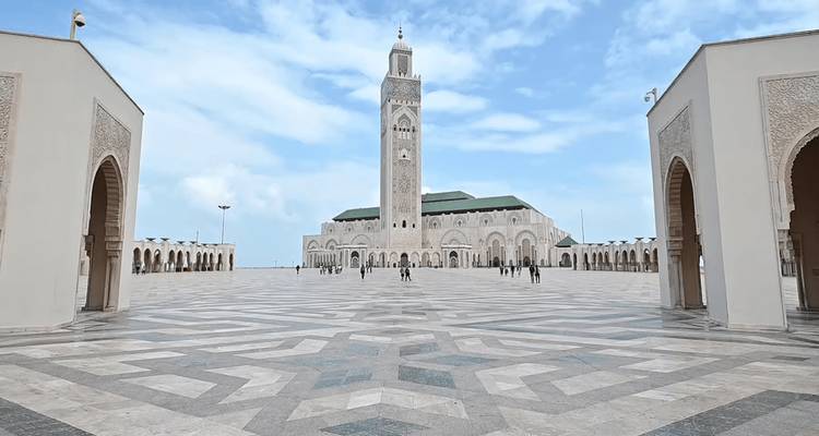 Vast marble courtyard framing the Hassan II Mosque under bright blue skies.