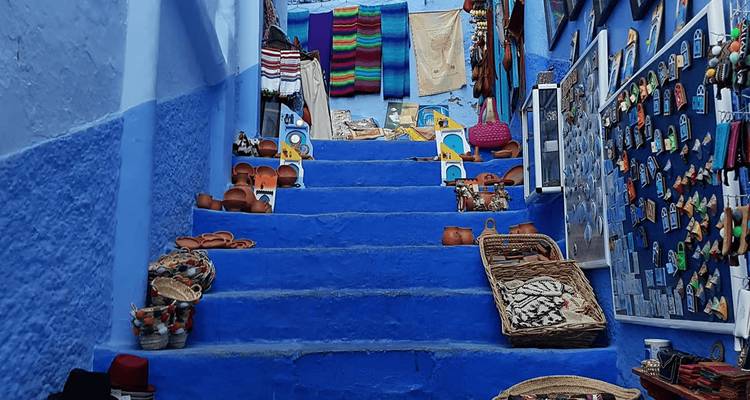 Blue staircase lined with local crafts and colorful textiles in a medina.