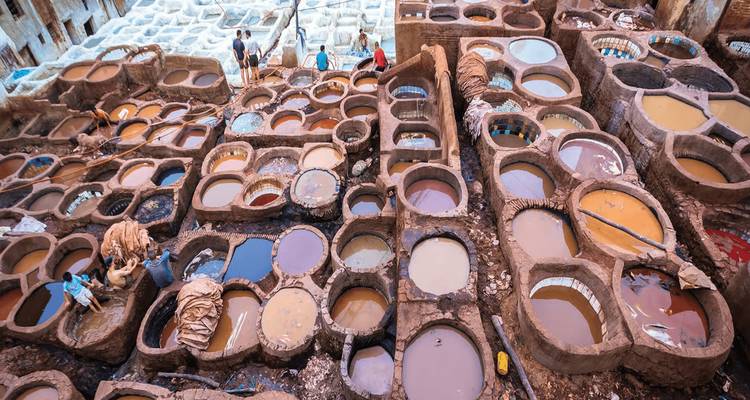 Close-up view of circular dye pits filled with colorful liquids at a tannery.