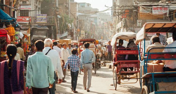 Belebte enge Straße in Alt-Delhi voller Fußgänger, Händler und Rikschas.