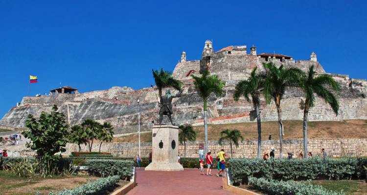 Les visiteurs se promènent devant les palmiers et les imposants murs de pierre du Castillo San Felipe à Carthagène.