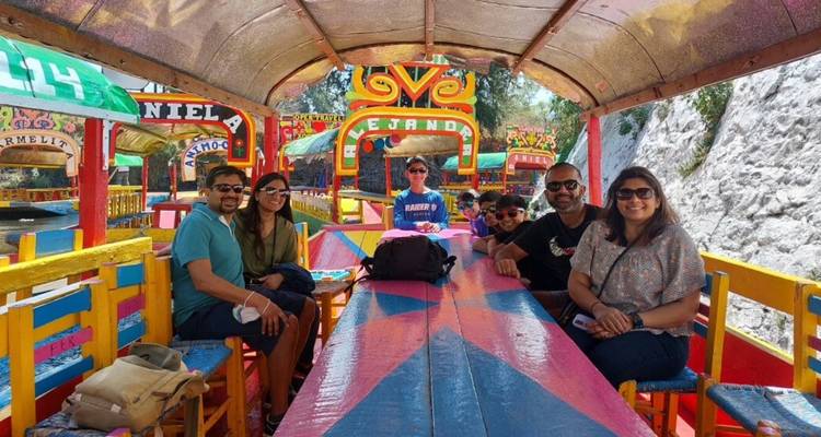 Reizigers ontspannen zich op een kleurrijk beschilderde trajinera boot langs de kanalen van Xochimilco.
