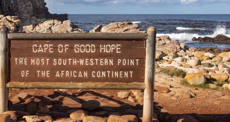 Wooden sign marking Cape of Good Hope, most south-western point of African continent, beside rocky shore.