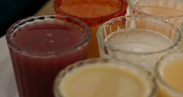 Nahaufnahme einer Auswahl traditioneller mexikanischer Pulque-Shots in Gläsern.