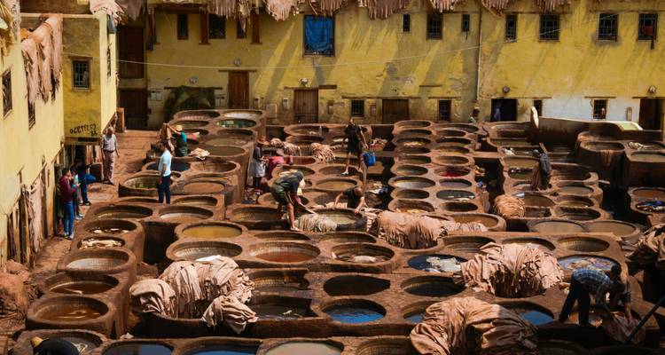 Drukke Chouara-loouwerij in Fes met arbeiders die huiden roeren en verven in ronde kuipen