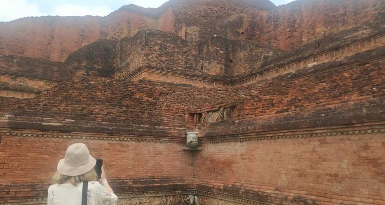 Touriste photographiant les ruines massives en briques rougeâtres d'un ancien complexe monastique bouddhiste