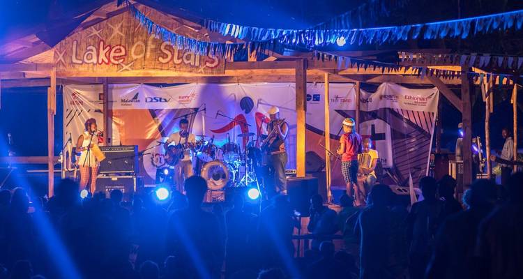 Colourful evening band performance on a wooden stage under a banner reading 'Lake of Stars'.
