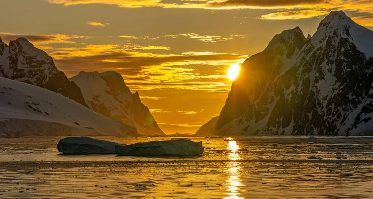 Coucher de soleil dramatique d'or sur les montagnes glacées et l'iceberg flottant dans les eaux de l'Antarctique