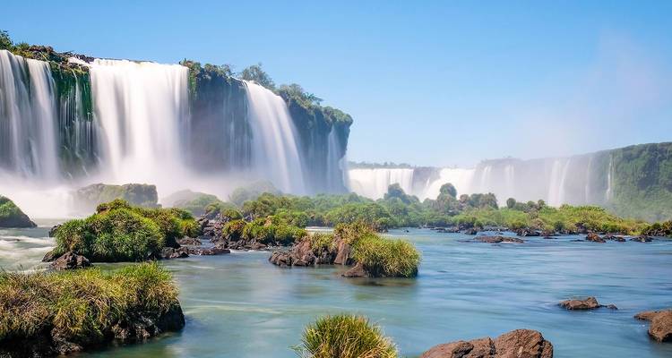 Powerful Iguazu Falls cascade into a misty river surrounded by lush greenery.