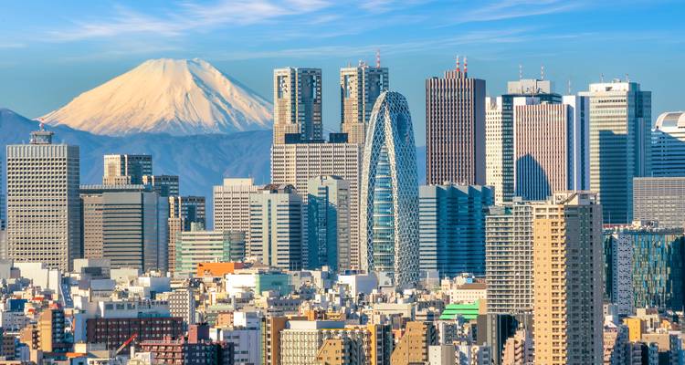 Tokyo skyline with modern towers and snow-topped Mount Fuji under a crisp blue sky.