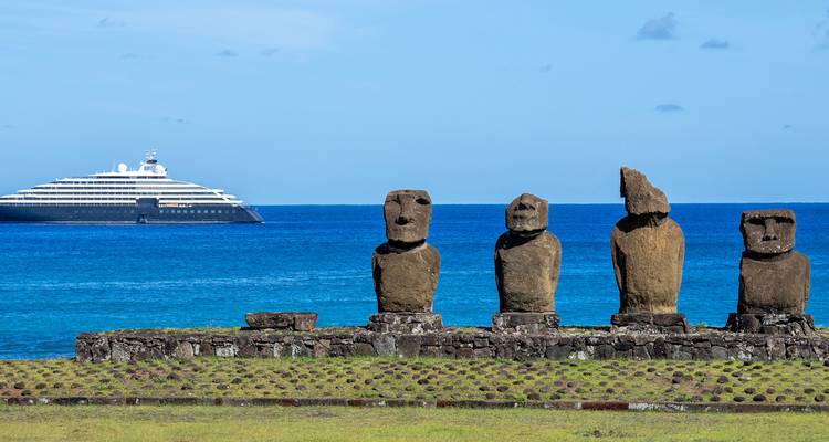 Row of Easter Island moai statues with sleek cruise yacht on blue Pacific horizon