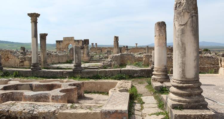 Antike römische Ruinen mit stehenden Säulen und Steinfundamenten in Volubilis, Marokko.